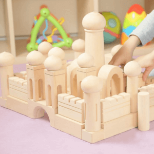 Child is building a magic castle from wooden blocks