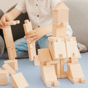 A boy is building a castle from wooden blocks using Smarty modular set